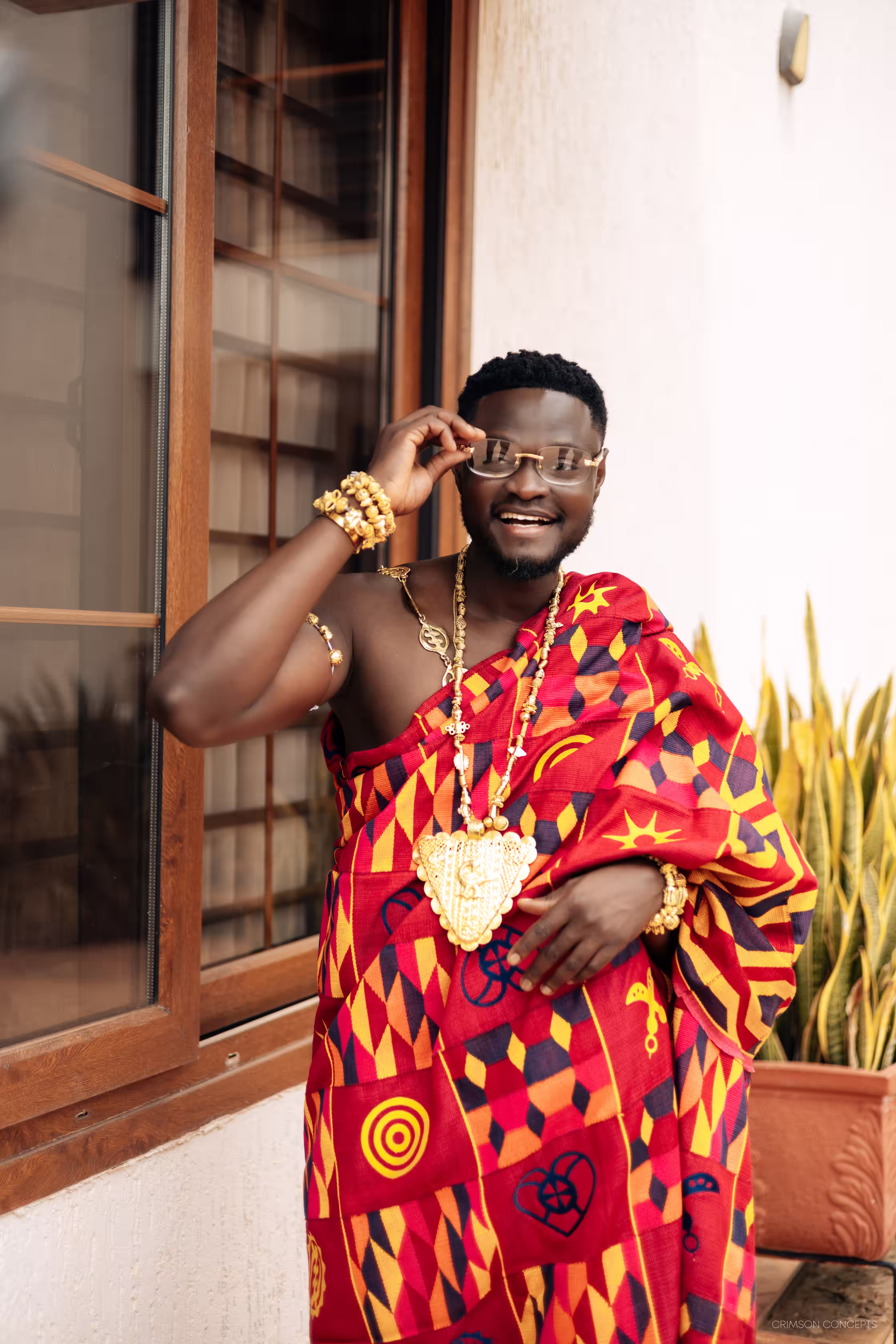 Qojoh laughing in kente cloth and gold jewelry ahead of the ceremony