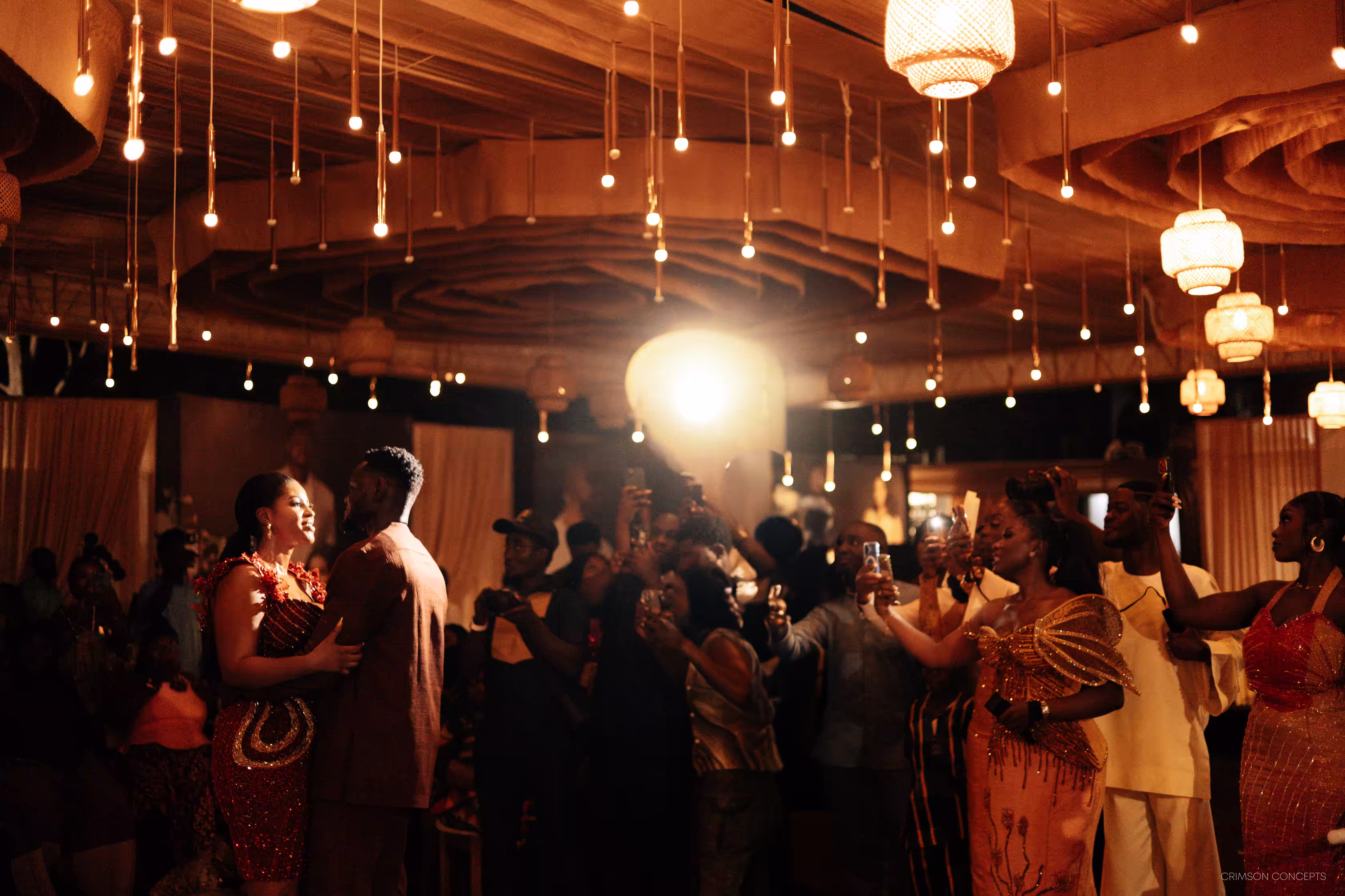 Guests dancing under string lights at Qojoh and Cassie's wedding reception in Kumasi